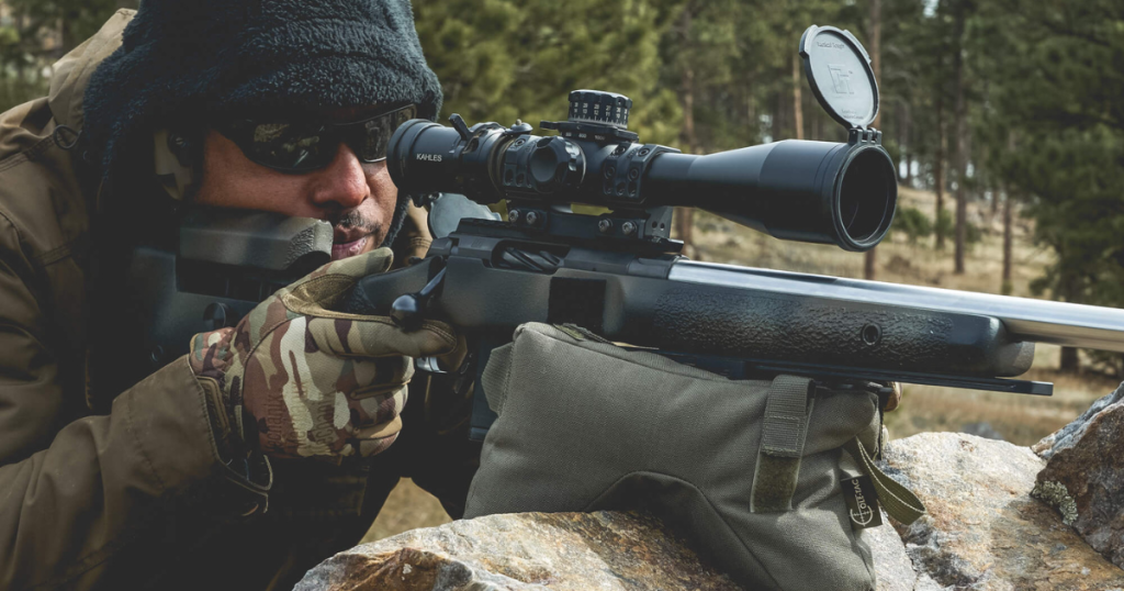 A man using a Cole-TAC support bag for his rifle on a rock.