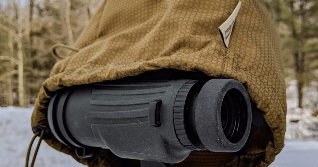 A pair of binoculars covered with a Cole-TAC Shower Cap to protect it from the wet snow.