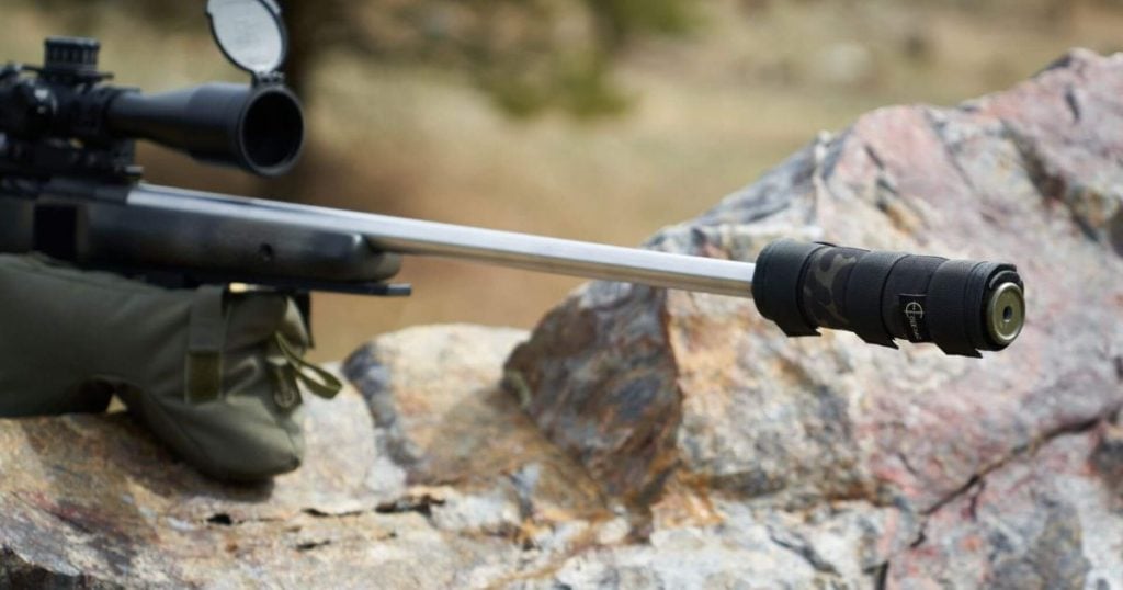 A rifle resting on a shooting bag with a suppressor and suppressor cover by Cole-TAC.