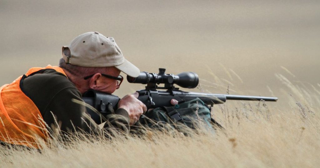 A man in a prone shooting position while hunting big game in the West.