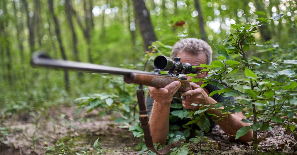A man in a prone position in western terrian hunting.