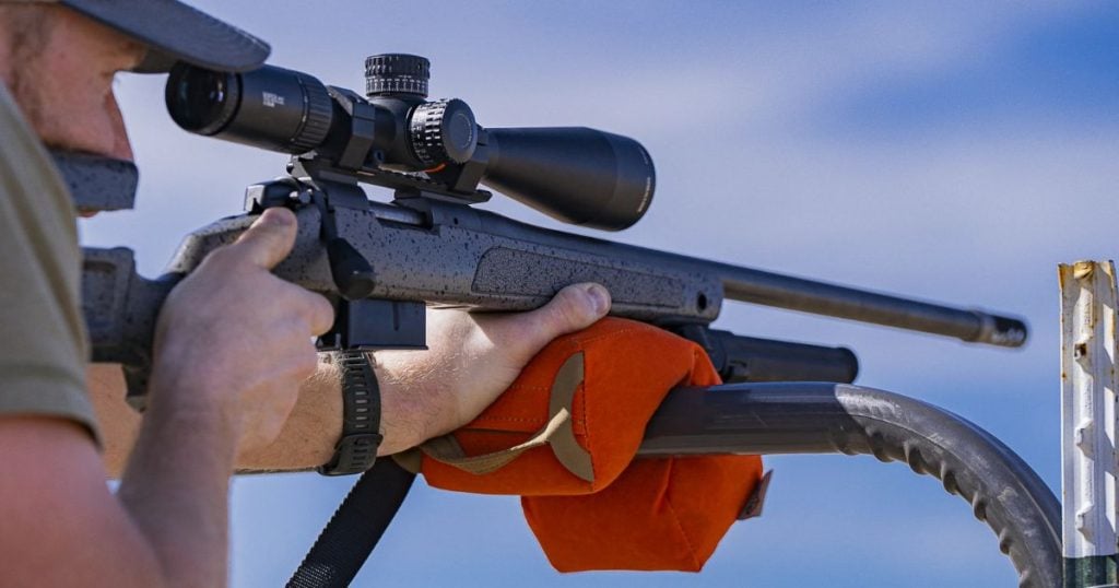 A shooter using a Cole-TAC Revolution support bag to steady his rifle on a pool.