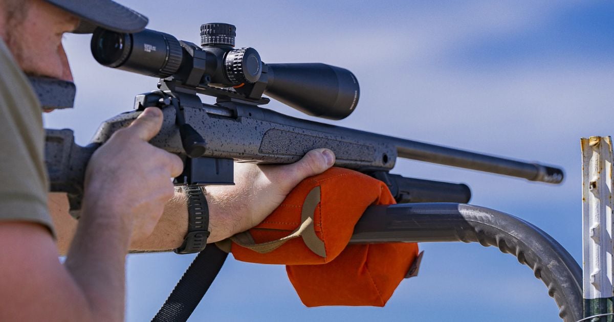 A man using a Cole-TAC Support Bag to stablize his rifle on a bar.