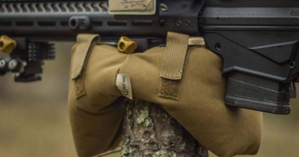 A Cole-TAC support bag resting on a branch with a rifle on top.
